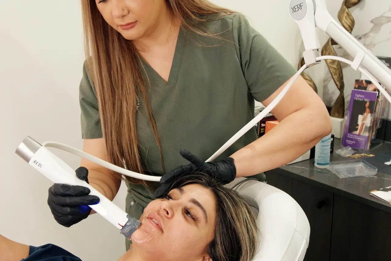 A practitioner working a radiofrequency handpiece along a client’s jawline