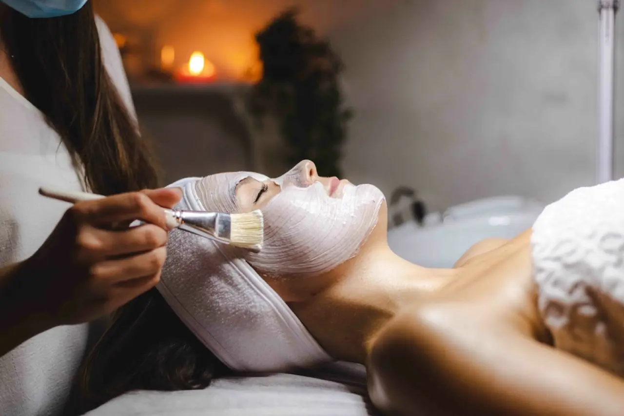 A practitioner brushing a cream mask onto a client’s face