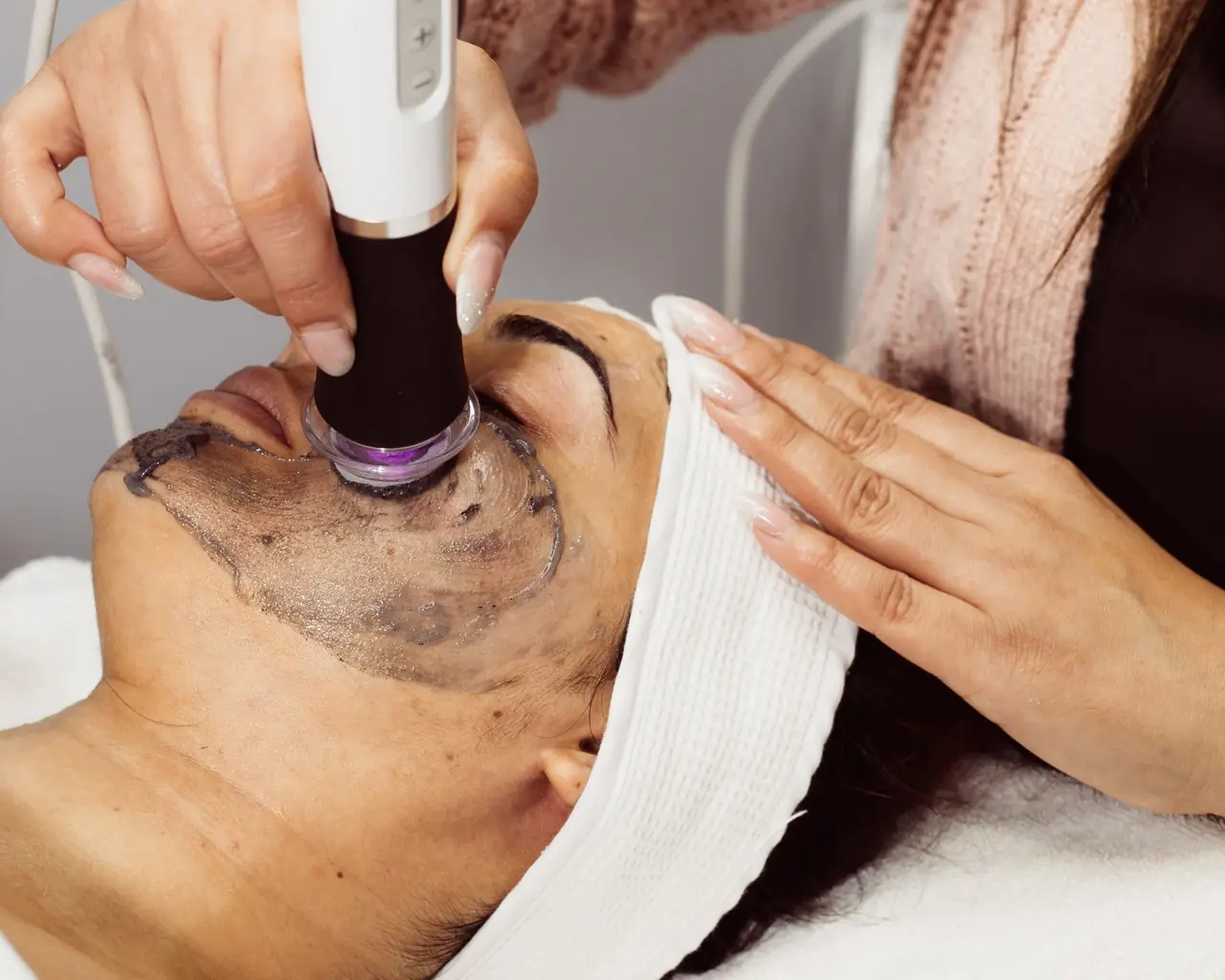 A laser handpiece passing over a carbon mask during a facial