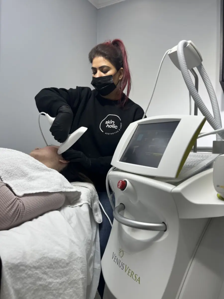 A practitioner beside a laser console during treatment