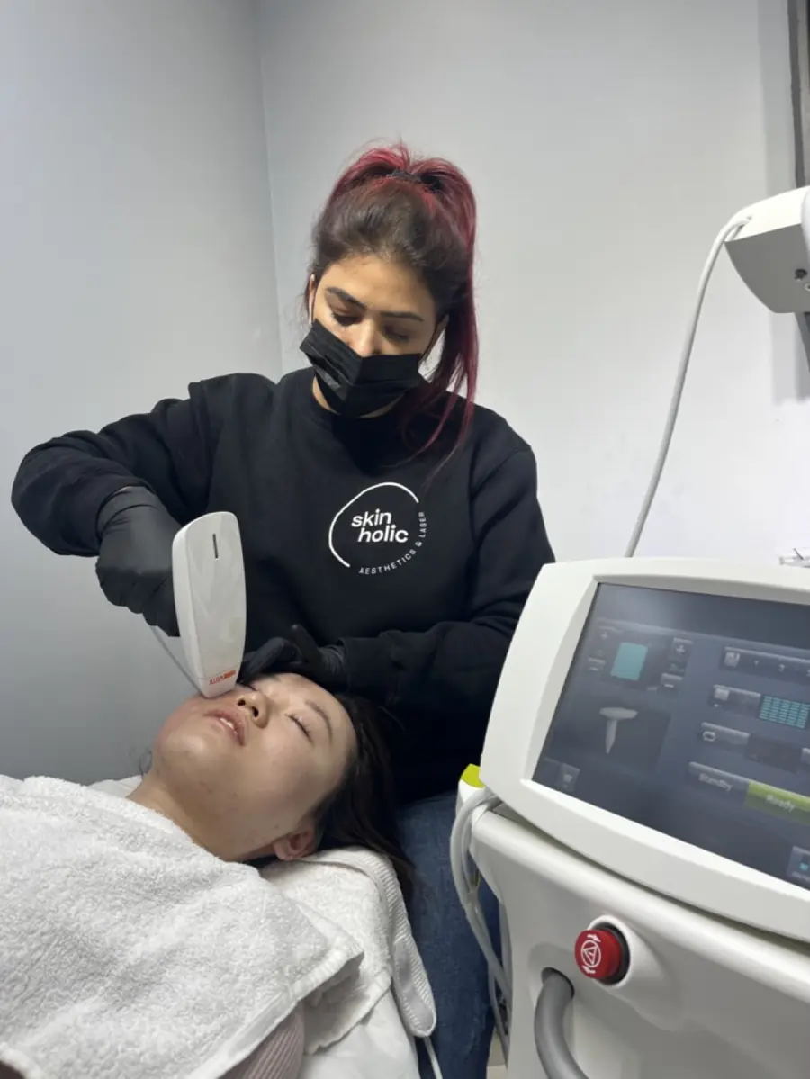 A practitioner using a radiofrequency handpiece on a client’s face